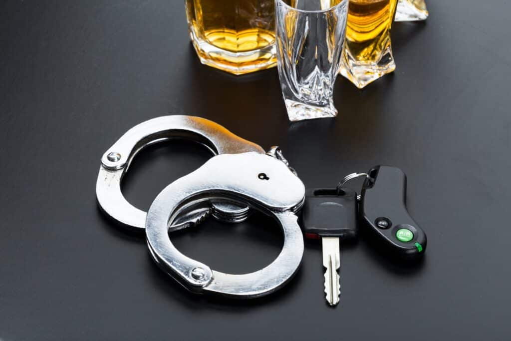 A set of handcuffs, car keys and alcoholic drinks, representing how one can benefit from calling a Portland criminal defense attorney.