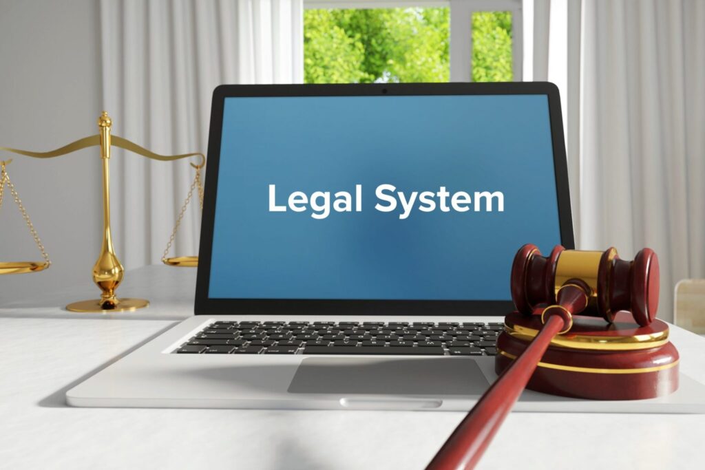 A laptop open with the words "Legal System" on it and a judge's gavel next to it, representing how one can benefit from calling a Portland criminal defense attorney.