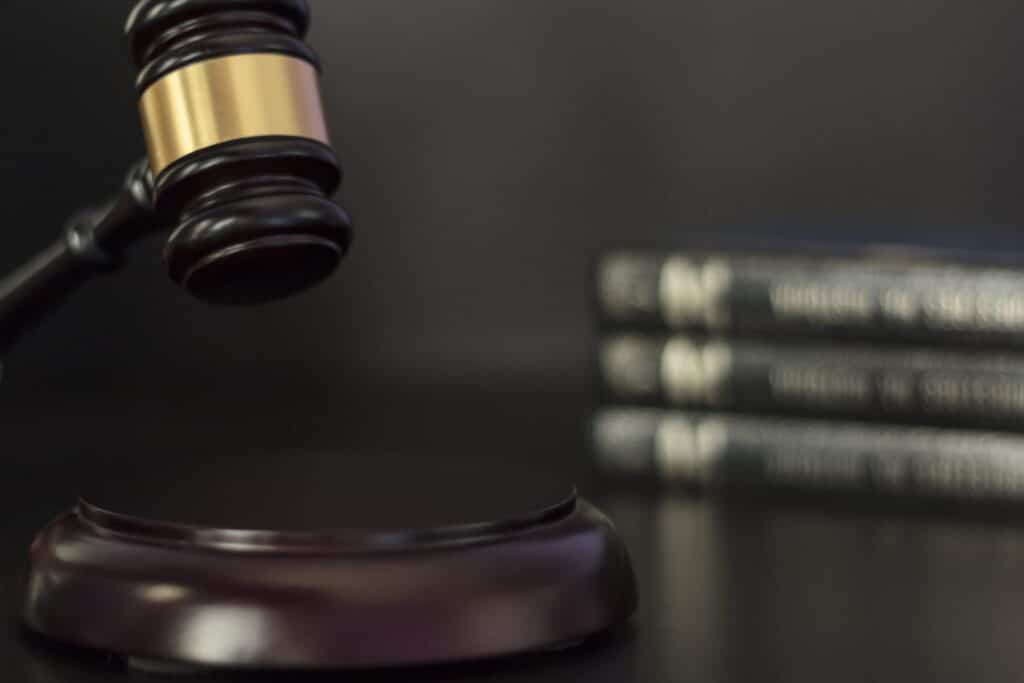 A judge's gavel about to hit a block with books in the background, representing how one can benefit from calling a Portland criminal defense lawyer.