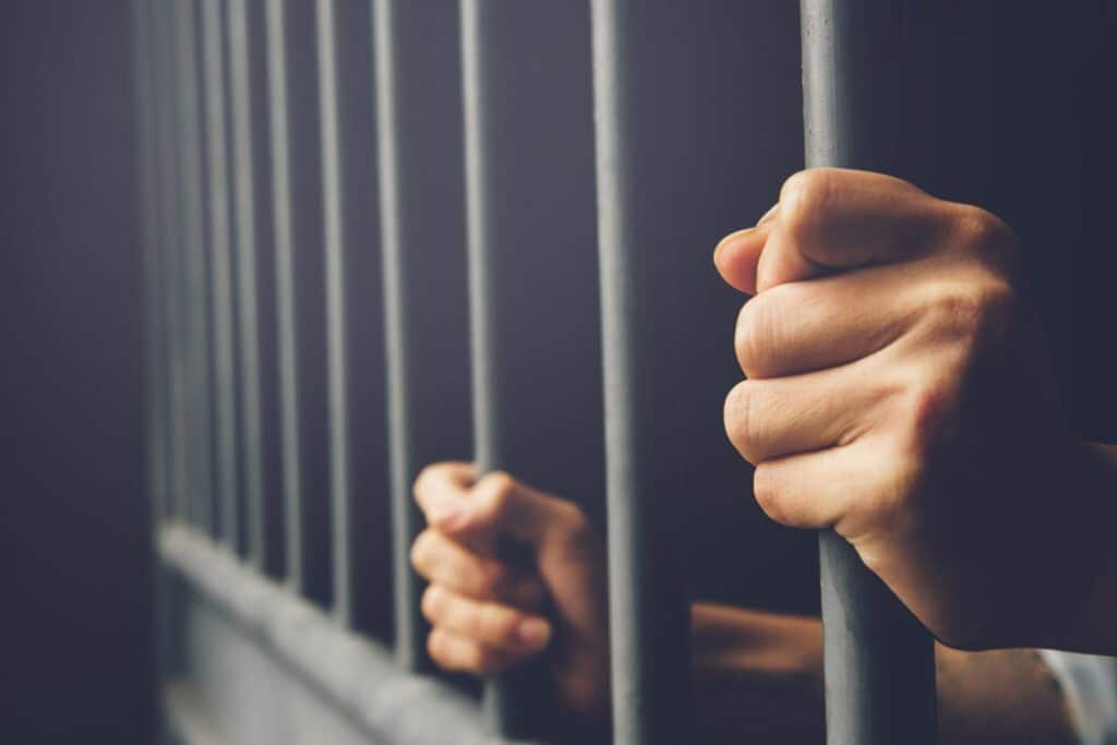 A person inside a jail holding the bars, representing how one can benefit from calling a Portland criminal defense lawyer.