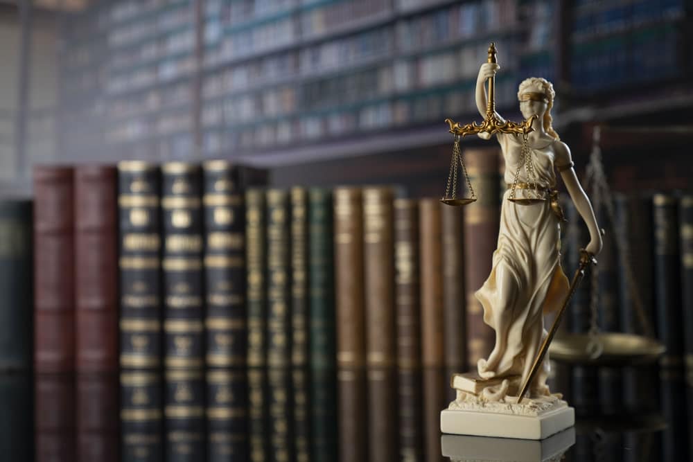 Aggravated Assault a Felony or Misdemeanor in Kennebunk Portland and Brunswick Maine portrayed by ivory lady justice statue in front of legal textbooks.