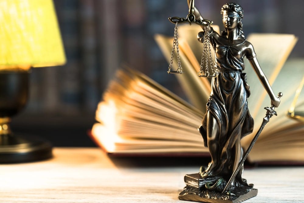 Domestic Violence Defense Lawyers in Kennebunk, Portland and Brunswick Maine Portrayed by a legal text and lady justice sitting on a table-top in law library.