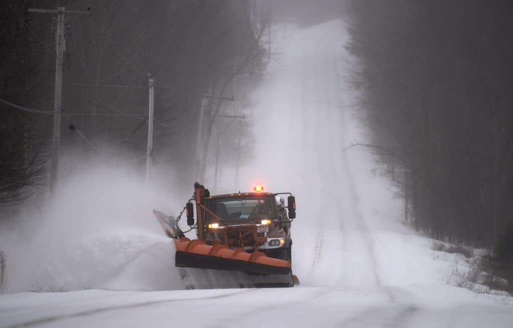 Skowhegan Woman Charged with OUI After Head-On Collision with Maine DOT Plow Truck depicted by a Maine snow plow removing snow on country road